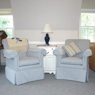 A cozy living room setup with two upholstered chairs, a small table, and a lamp.