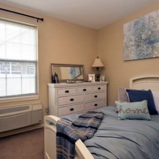 A cozy bedroom with a bed, dresser, and decorative elements.