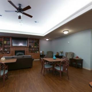 A cozy living room with a ceiling fan, television, and comfortable seating arrangements on a wooden floor.