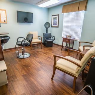 A well-lit waiting room with comfortable chairs, a television, and wooden flooring.