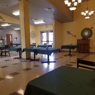 An empty dining area with green tables and warm lighting.