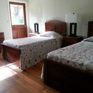 A cozy bedroom with twin beds, wooden furniture, and ample natural light.
