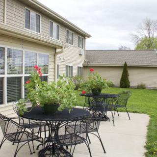 A cozy patio setup with metal tables and chairs adorned with potted plants in a backyard.