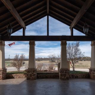 A scenic view from inside a pavilion with columns, overlooking a landscaped area.