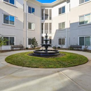 A peaceful courtyard featuring a central fountain with surrounding benches and a modern building exterior.