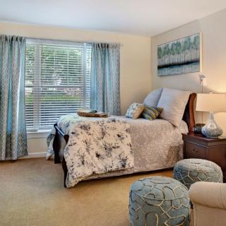 A cozy and elegantly decorated bedroom with a large window, featuring tasteful decor and comfortable furnishings.