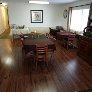 A cozy dining area with neatly arranged tables and chairs on a polished hardwood floor.