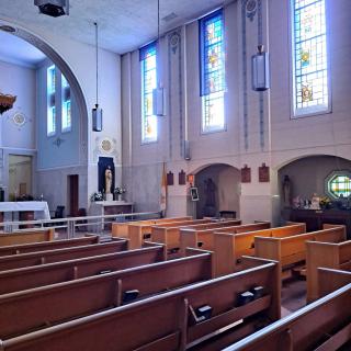 The interior of a church with wooden pews and colorful stained glass windows.