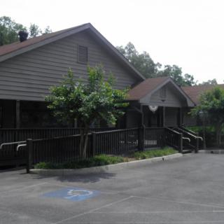 A view of a building with a parking lot and surrounding trees.