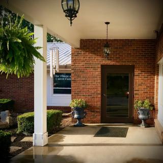 A brick building entrance with decorative plants and hanging lights.