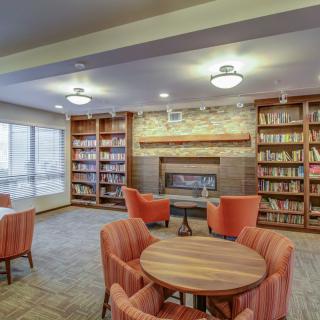 A cozy library with bookshelves, a fireplace, and comfortable seating for reading.