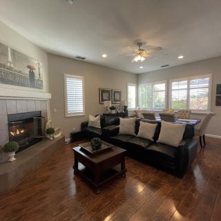 A cozy living room with a large sofa, fireplace, and wooden flooring.