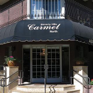 An exterior view of the entrance to Carmel Residence with a black awning.