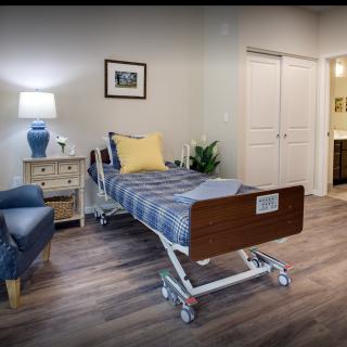 A well-furnished hospital room with a bed, lamp, and cozy decor.