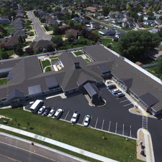 Aerial view of a modern building surrounded by a parking lot and residential neighborhood.