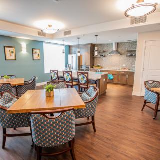 A modern and cozy dining area with a connected kitchen, featuring elegant furniture and bright lighting.