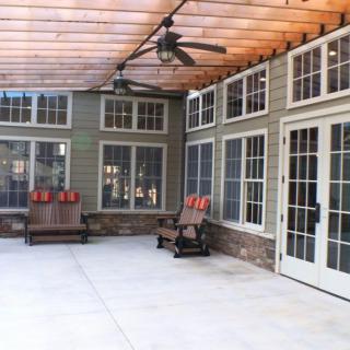A covered patio with ample windows, seating areas, and a ceiling fan.