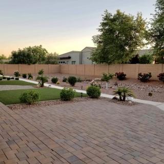A beautifully landscaped backyard with paved walkways and greenery at sunset.