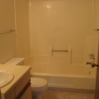 A simple bathroom setup with a bathtub, sink, and toilet.