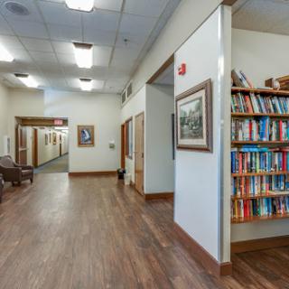 A well-lit hallway featuring a bookshelf and framed artwork.