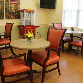 A cozy dining area with tables and chairs, featuring a popcorn machine and flowers as decoration.