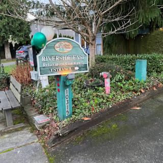 A welcoming community sign amidst lush greenery, indicating the entrance to a local establishment.
