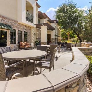 A sunny patio area with tables and chairs next to a modern building.