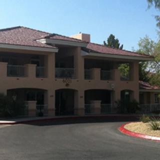 A two-story residential building with balconies and a paved driveway.