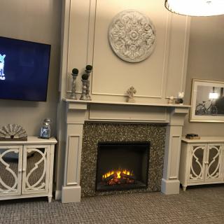 A cozy living room featuring a lit fireplace, wall-mounted television, and elegant decor.