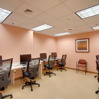 A computer lab with multiple workstations and office chairs in a well-lit room.