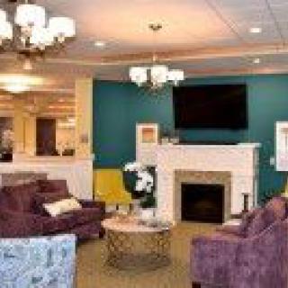 A cozy living room with comfortable seating, a fireplace, and a television mounted on the wall.