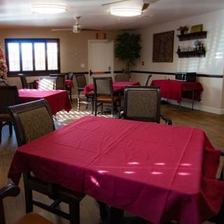 A cozy dining room with tables covered in red tablecloths and various seating arrangements.