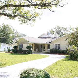 A suburban house with a driveway and well-maintained lawn surrounded by trees.