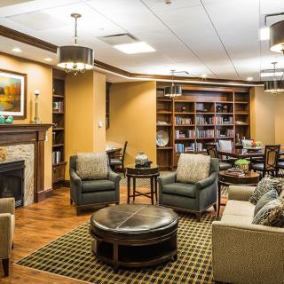 A cozy and well-furnished living room with a library section, featuring comfortable seating, a fireplace, and bookshelves.