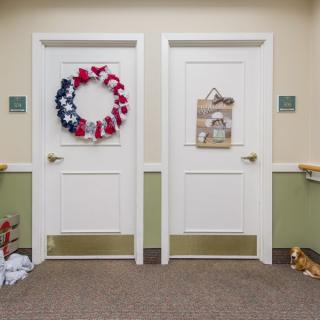 Two decorated doors in a hallway, one with a festive wreath and the other with a wall hanging.
