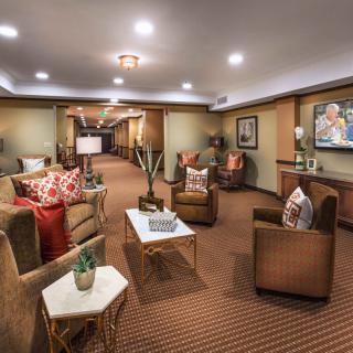 A cozy living room with comfortable seating and warm lighting, featuring decorative pillows and artwork on the walls.