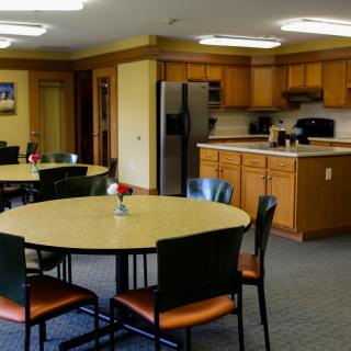 A communal kitchen and dining area with tables, chairs, and appliances.