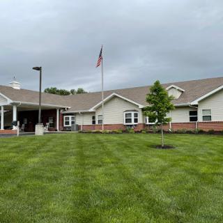 A well-maintained residential building with a flag in the foreground and lush green landscaping.