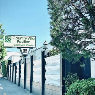 A view of the Country Villa Pavilion sign and entrance, surrounded by trees and a sidewalk.