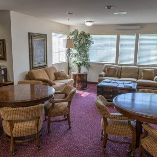 A cozy living room with sofas, chairs, tables, and a carpet.