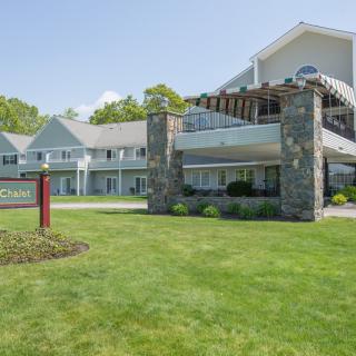 A modern building with stone pillars and a well-maintained lawn on a clear day.