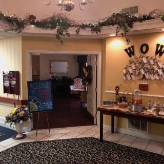 A warmly decorated entranceway with holiday garlands, a 'WOW' sign on the wall, and a table displaying various items.