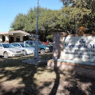 Entrance of a healthcare facility with parked cars and a prominent sign.