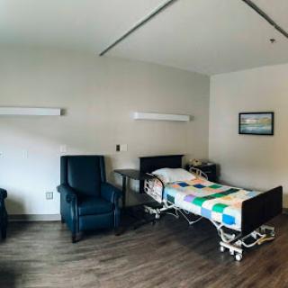 A view of a hospital room equipped with a bed and seating for visitors.