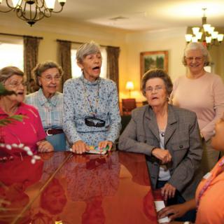 A group of senior women gathered around a table, engaged in conversation.