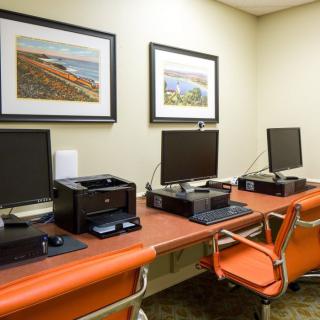 A modern office space featuring multiple computer stations with printers and orange chairs.