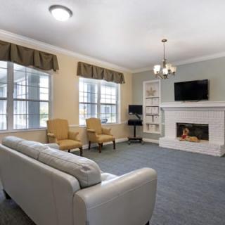 A cozy living room with a fireplace, sofa, chairs, and a television.