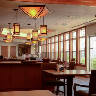 A warm and inviting restaurant interior featuring stylish lighting and large windows.
