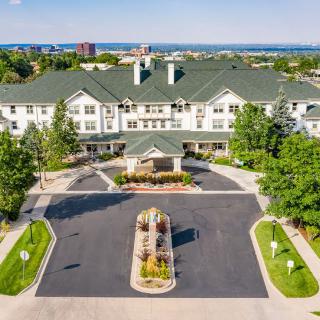 Aerial view of a large residential building with a landscaped driveway and surrounding greenery.