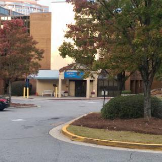 A view of a building entrance with surrounding trees and a parking area, showcasing an autumn atmosphere.